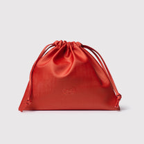 Bolsa de cetim vermelha com logo GE Beauty em fundo cinza claro.